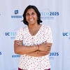 Conference Chair, Azra Ayers, smiling in front of the UC Tech backdrop.