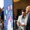 Attendee talking to sponsor representatives at their booth.