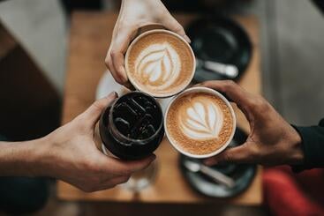 Aerial view of three hands holding cups of coffee 
