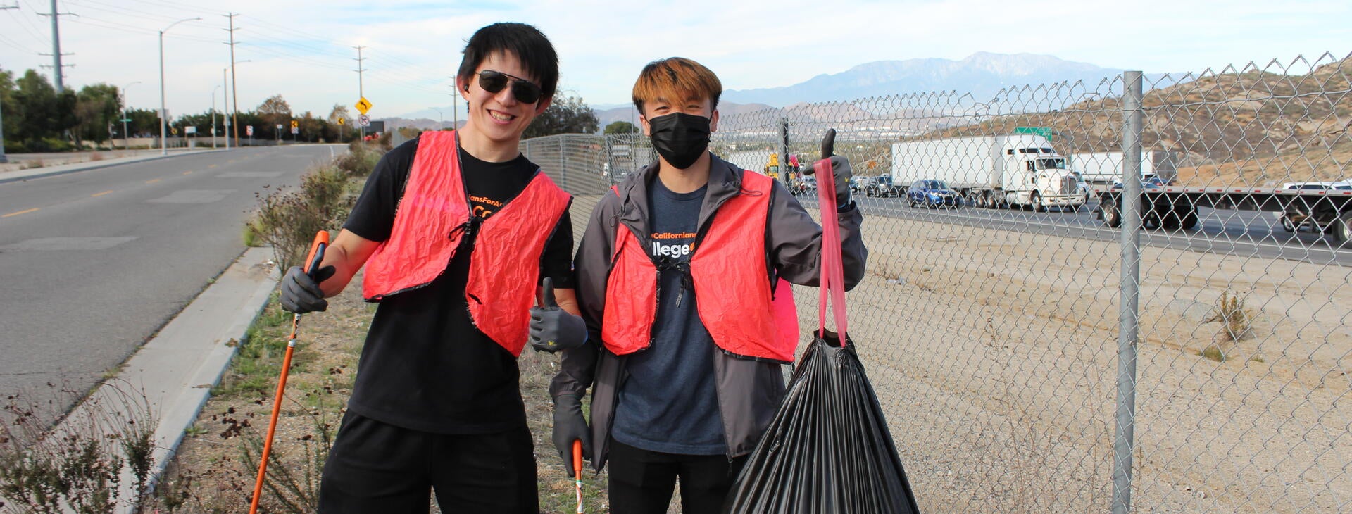 two men holding up a trashbag