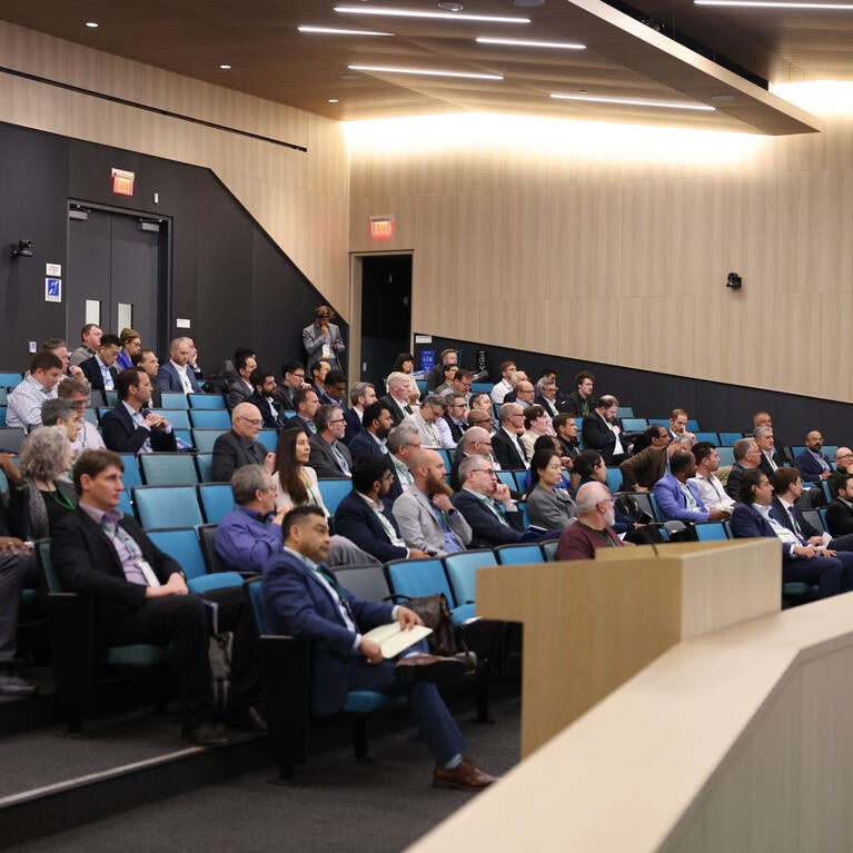 Audience members listen to a presentation in a large lecture hall during the Inaugural Hydrogen Engine Alliance – North America Conference, with keynote speaker Professor Thomas Koch presenting at the front.