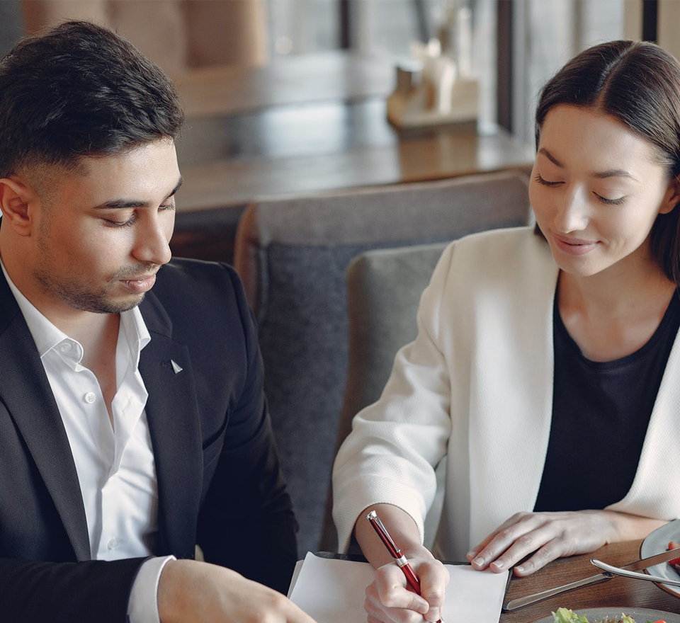 Young Hispanic  business man and woman writing at a desk in an office
