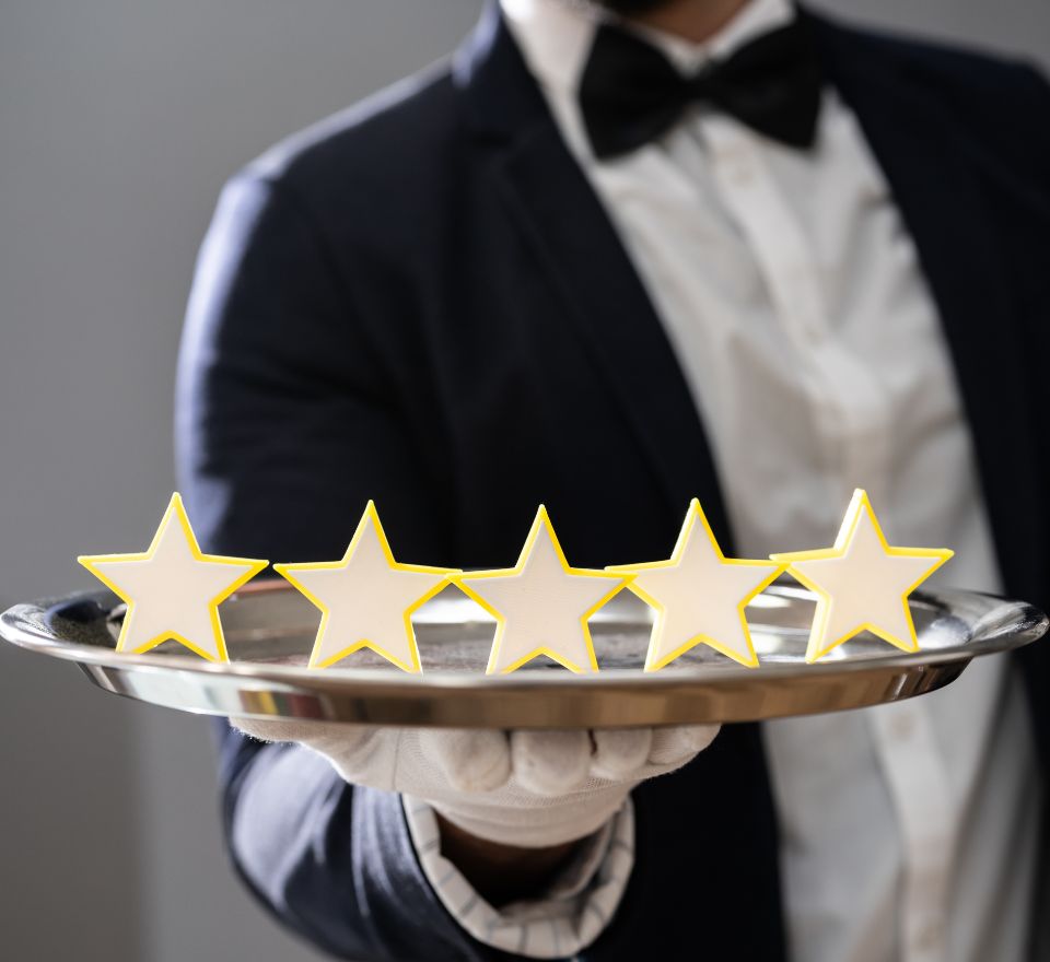 Waiter holding silver tray with 5 stars indicating stellar service in hospitality