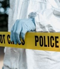 Medical professional with a glove on holding a police do not cross tape