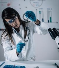Forensic nurse inspecting a blood droplet on a pair of handcuffs in a lab room