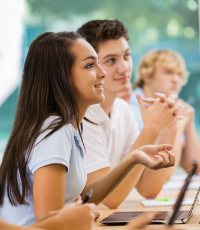 Middle school girl and boy at desk in a classroom listening to lecture