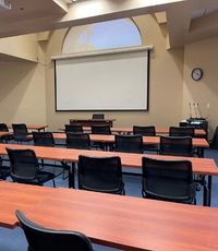 EUV classroom with rows of empty tables and chairs looking at the large screen at the front of the room