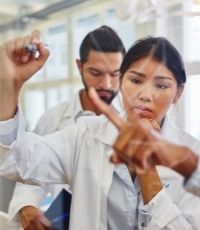 Two forensic nurses one male one female discussing a case and writing notes on a board