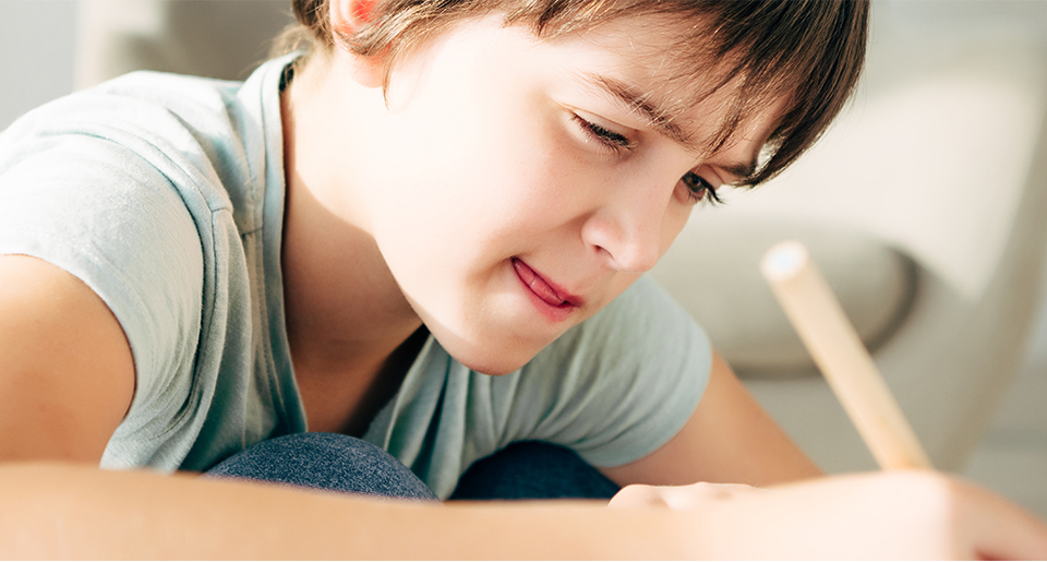 Up close side view of a White grade school boy writing