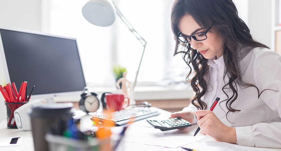 Young business women wearing glasses as she sits at a desk writing