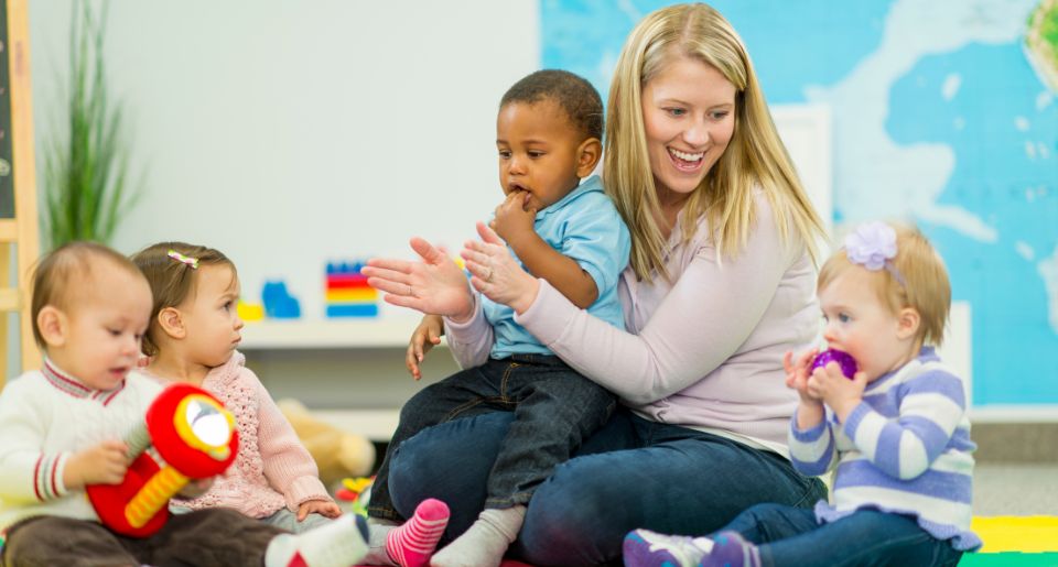 Early childcare teacher on the floor teaching young students