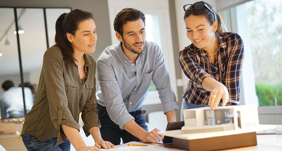 Two young White women and a man looking down at the same thing