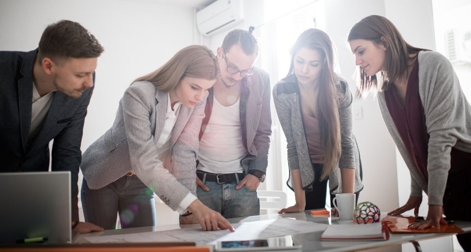 Diverse group of business people at a table talking as they all look down at something