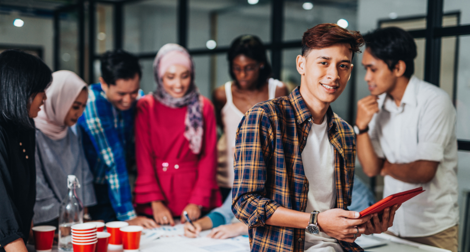 Group of ethnically diverse students standing around a table talking