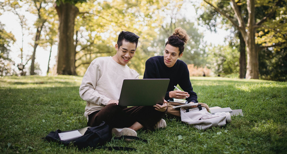Two young men studying on laptop outside