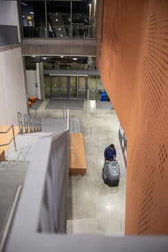 Custodial riding cleaning equipment in lobby of large building