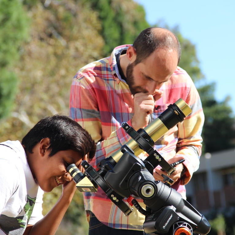 “Fiesta Familiar: Explorando La Ciencia Juntos” on May 19 at UC Riverside will include activities such as viewing solar explosions through a telescope. Seen here are Mario De Leo-Winkler, lead organizer of Fiesta Familiar, and a future astronomer.